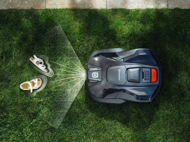 Husqvarna Automower 308V vu de dessus sur la pelouse, détectant des chaussures grâce à sa caméra